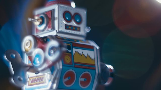 An antique cheerful colorful metal clockwork robot goes on a black background with colorful sparkling lights. Macro. Closeup. Shallow depth of field  