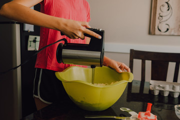 dos manos de niña rompiendo un huevo preparando tortitas