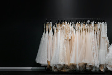 Wedding dresses made of silk chiffon, tulle and lace. Beautiful White cream bridal dress on hangers in wedding salon. Photo with empty space left side for text of advertise