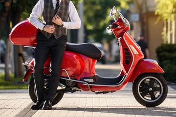 Poster man in klassiek vest in de buurt van een rode vintage motorscooter. © Med Photo Studio