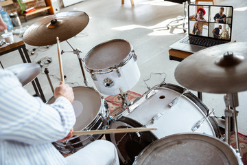 Caucasian musician playing drumms during online concert at home isolated and quarantined. Using camera, laptop, streaming, recording courses. Concept of art, support, music, hobby, education.