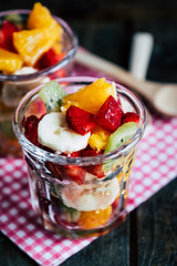 Salade de fruits colorée fait maison dans un verre transparent avec des fraises kiwis bananes et oranges 