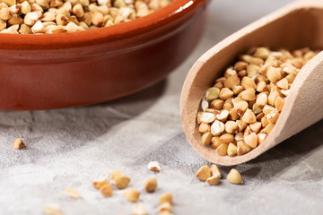 Raw green buckwheat in a brown clay plate on a brown background. Vegan organic food concept, diet, weight loss, healthy and proper nutrition