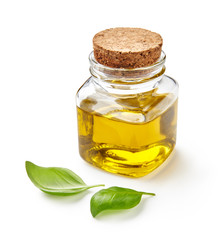 Glass jar of olive or vegetable oil with basil leaves isolated on white.