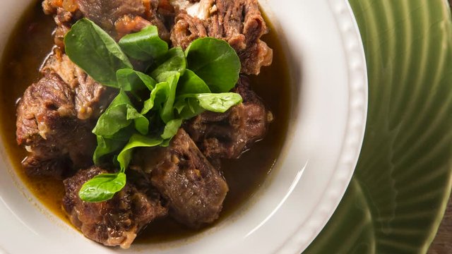 Brazilian traditional food called oxtail with arugula. Top view with smoke.