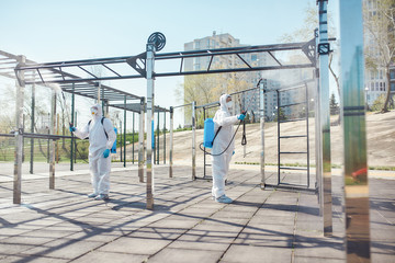 Safety is our Priority. Sanitization, cleaning and disinfection of the city due to the emergence of the Covid19 virus. Specialized team in protective suits and masks at work near sports ground