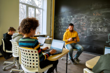 Educating Students For Success In A Changing World. Portrait of pupils listening to their tutor, while sitting with laptops during a lesson in modern smart school. Selective focus