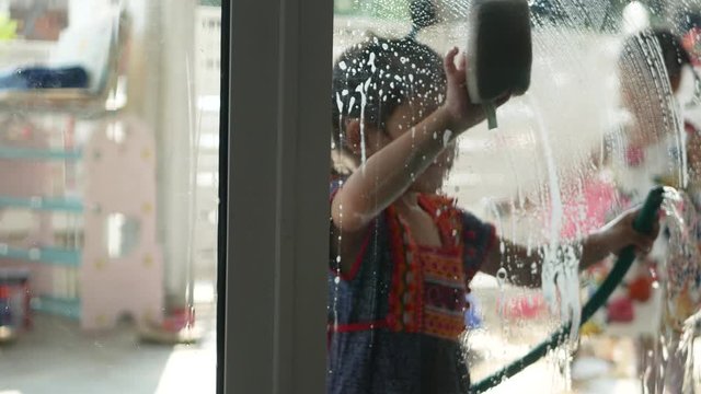 Sliding door being cleaned by little baby girl - child's development by letting them do household chores