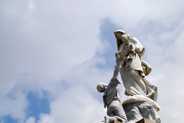 heroic style madonna sculpture against cloudy sky