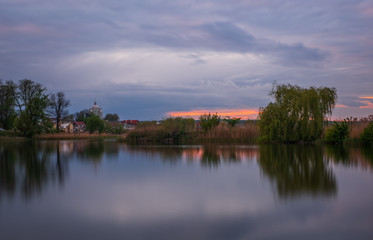 Fototapeta na wymiar Long exposure sunset view on Ivano-Frankove (Yaniv), Yanivskyi Stav Lake and forest. Roztochia Biosphere Reserve, Lviv district, Ukraine. May 2020