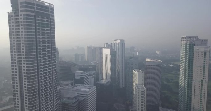 Ungraded, Ascending aerial flight over high rise buildings towards busy metropolitan city