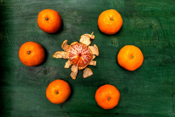 unpeeled tangerines surround a peeled tangerine