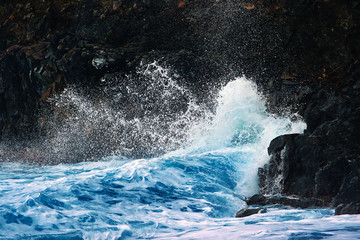 Fototapeta na wymiar Ocean waves breaking on the black volcanic cliffs, stormy day. Storm season, seascape. Waves breaking on the black rocks