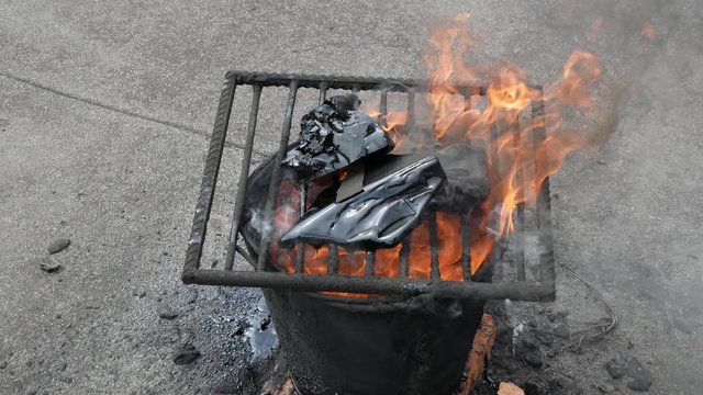 Molten hot tar in a bucket on the bricks. Roof repair. Fire from bucket. Grid on bucket