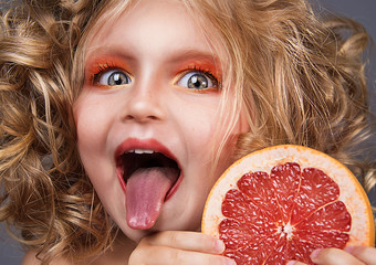 close up portrait of beautiful little girl with grapefruit
