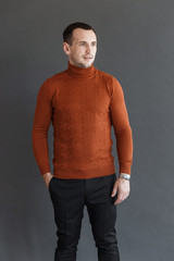 Obraz premium man in an orange sweater on a gray background