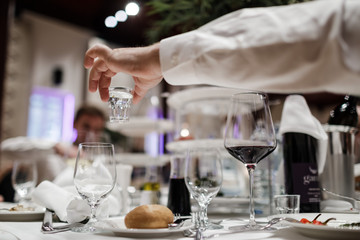 A glass of vodka in the man's hand during the banquet. Festive table with alcohol.