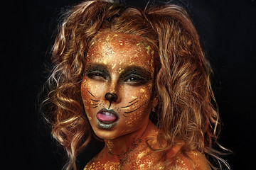child with professional gold face painting. studio close up portrait of blonde girl with art.cat