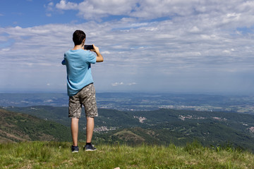 a guy takes a landscape picture with his cell phone from a vantage point
