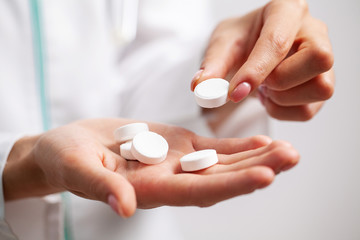 Doctor close up holding white pills for weight loss