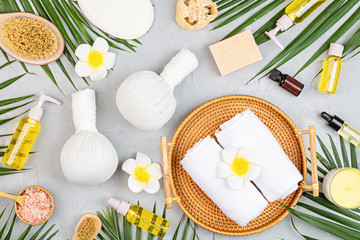 Spa massage Aromatherapy body care background. Spa herbal balls, cosmetics, towel and tropical leaves on gray concrete table. Top view, flat lay, overhead, copy space. Beauty and health care concept