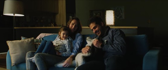 Family of three - father, mother and daughter wathcing TV in the evening. Pet husky dog lying near them. Togetherness, quarantine, stay home