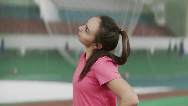 Young Athlete Girl turns on the timer on the clock and Stretchs