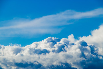 Fototapeta premium White fluffy cumulus clouds against a blue sky. A symbol of dreams and freedom. Background for design.