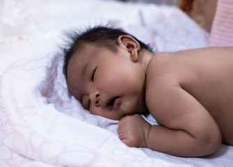 Fototapeta na wymiar Newborn baby sleeping on soft cotton cloth,blurry light around
