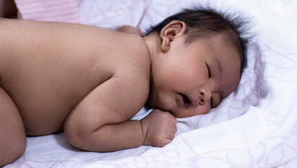 Fototapeta na wymiar Newborn baby sleeping on soft cotton cloth,blurry light around