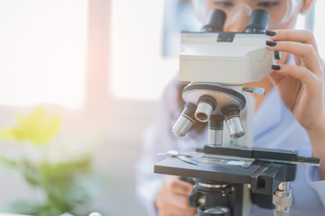 Asian Lab assistant and veterinarian examining tissue sample under the microscope in a laboratory. Young scientists do some research. Smiling woman in protective uniform.Science investigation concept