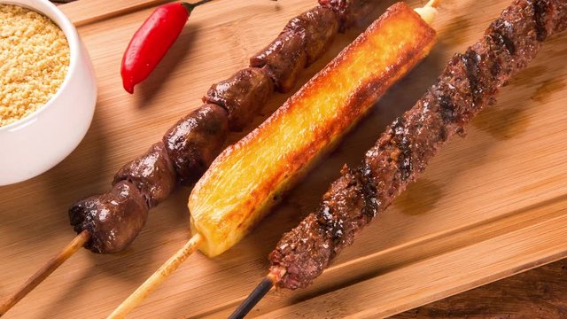 Assorted steak skewers on top of a board. Barbecue with smoke.