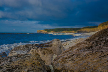 Fototapeta na wymiar Close-up Of Rocks At Beach Against Cloudy Sky