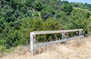 an abandoned wooden fence used as a dead end road  barrier on a lush steep green hillside with copy space