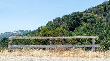 an abandoned wooden fence used as a dead end road  barrier on a lush steep green hillside with copy...