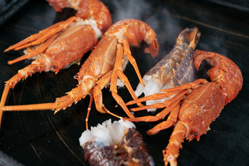 Sizzling hot cooking on the griddle pan. Delicious grilled halved Lobster with butter. Fresh, juicy and tasty Maine Lobster or Crayfish.