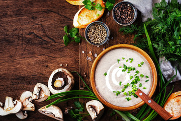 Creamy Mushroom Soup with croutons and chives on rustic wooden background