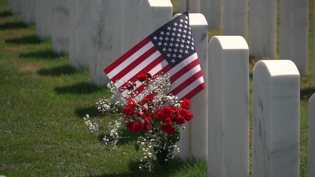 A US Flag And Fresh Flowers At A Military Graveyard