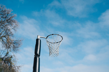 Netball goal ring and net against a blue sky and clouds at Hagley park, Christchurch, New zealand.