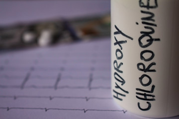 Pills on an electrocardiogram. One hundred dollar bills on an EKG. Container with the text...