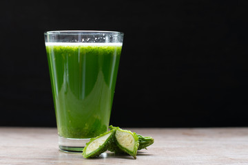 Herbal juice with bitter melon or bitter gourd on black background.