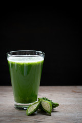 Herbal juice with bitter melon or bitter gourd on black background.