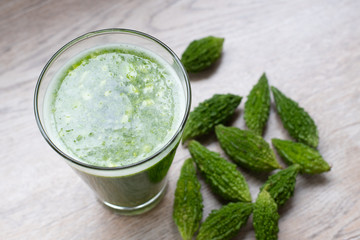 Herbal juice with bitter melon or bitter gourd on wooden background.