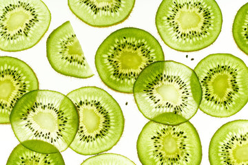 Backlit kiwi fruit slices on white background. Top view layout