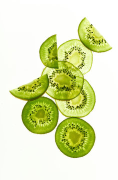 Backlit kiwi fruit slices on white background. Top view layout
