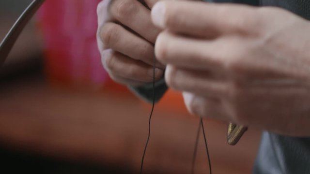 Close up of man uses a needle to crafts a brown leather belt in the leather workshop. Working process of the leather belt in the leather workshop.