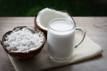 Coconut and a glass of coconut milk on a wooden background. Healthy food.