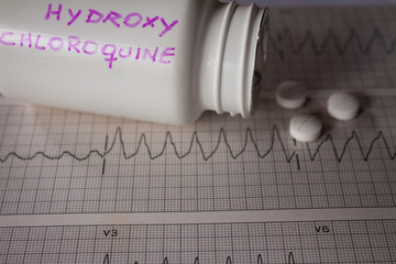 Adverse effects on the heart by hydroxychloroquine or chloroquine. Pills on an electrocardiogram...