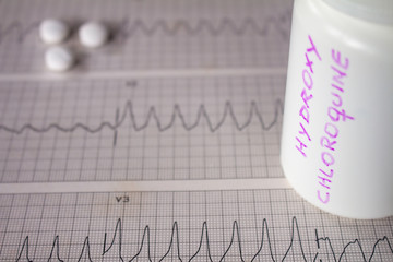 Adverse effects on the heart by hydroxychloroquine or chloroquine. Pills on an electrocardiogram...