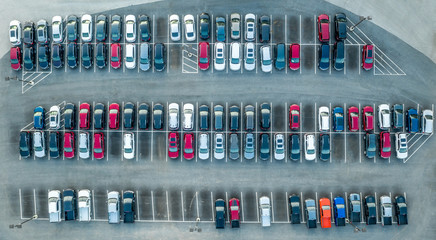 Aerial top down view of new red, black, white, blue cars parked in a row in a parking lot